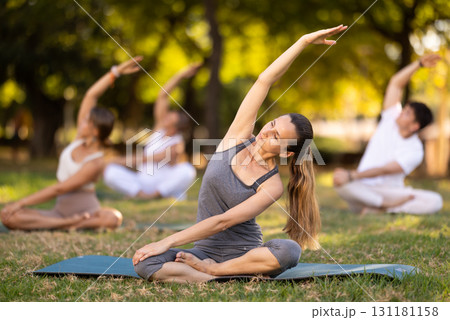 Yoga lesson visitors with girl coach perform padmasana in park 131181158
