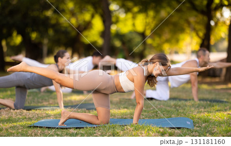 Girl doing balancing table pose during group yoga session in park 131181160