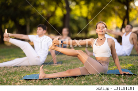 Girl participating in outdoor group yoga session in summer park Girl participating in outdoor group yoga session in summer park 131181191