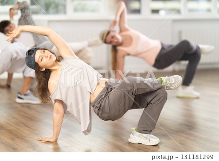 Girl and her students perform hip hop dance on one bent leg, movement in horizontal plane near floor 131181299