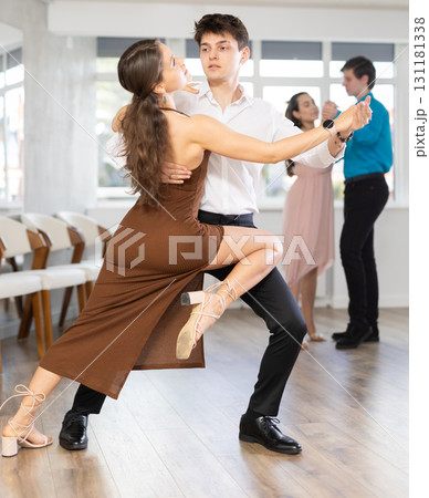 Girl and guy in festive clothes dancing slow ballroom dance during group lesson in choreography studio 131181338