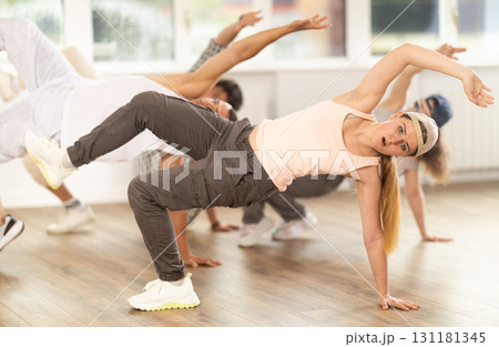Girl and her students perform hip hop dance on one bent leg, movement in horizontal plane near floor Girl and her students perform hip hop dance on one bent leg, movement in horizontal plane near floor 131181345