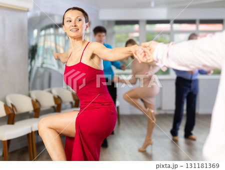 Happy woman enjoying active dancing in pair in dance studio Happy woman enjoying active dancing in pair in dance studio 131181369
