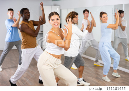 Group of active women and men practicing energetic dance in modern dance studio Group of active women and men practicing energetic dance in modern dance studio 131181435