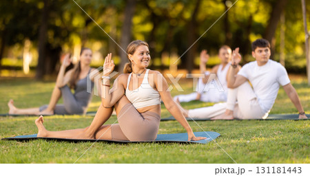 Girl performing twisting asana Matsyendrasana on green meadow Girl performing twisting asana Matsyendrasana on green meadow 131181443