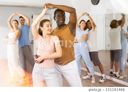 Positive smiling dancing couple enjoying active dancing during group training in dance hall 131181466