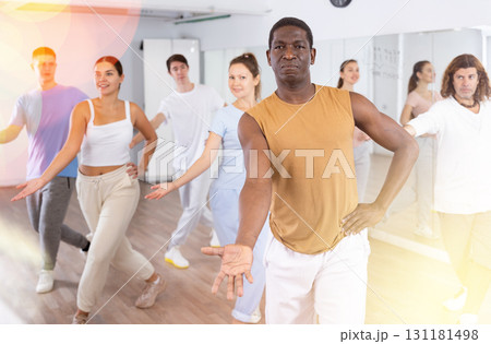 Cheerful multiracial people stretching out hand during dancing training in studio Cheerful multiracial people stretching out hand during dancing training in studio 131181498
