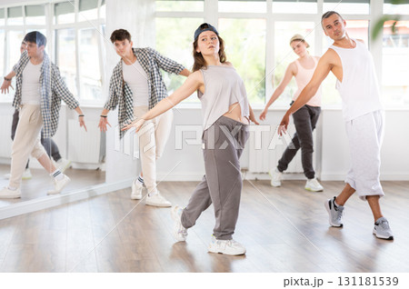 Dance group in casual clothes training to dance hip-hop and breakdance together in dance center 131181539