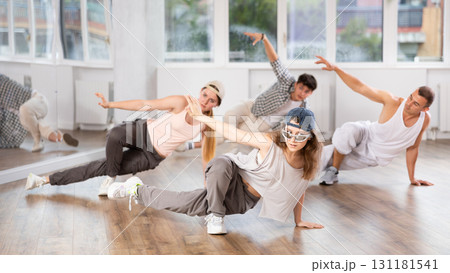 Girl and her students perform hip hop dance on one bent leg, movement in horizontal plane near floor Girl and her students perform hip hop dance on one bent leg, movement in horizontal plane near floor 131181541