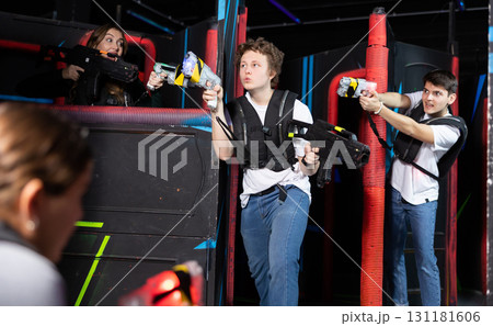 Two guys and one girl running and dodging while playing lasertag 131181606