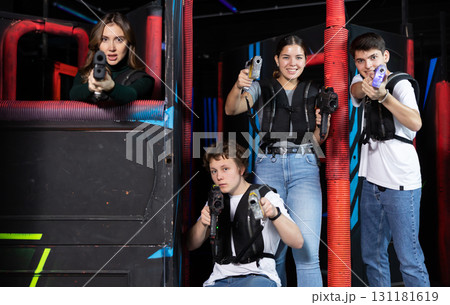 Two girls and two guys posing with lasertag guns in arena 131181619