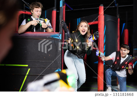 Portrait of excited people playing enthusiastically laser tag game two teams opposite each other in room 131181668