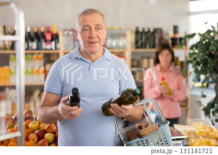 Grocery shopping at supermarket - man chooses olive oil while his wife chooses juice 131181721