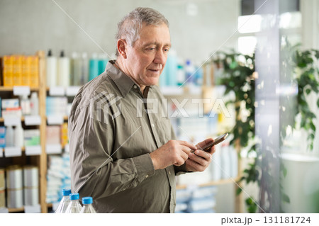 Senior man with phone is shopping in pharmacy Senior man with phone is shopping in pharmacy 131181724