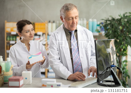 Male and female pharmacists looking for pills on computer 131181751