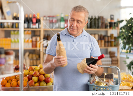 Senior man hold bottle and choose consider wine in store Senior man hold bottle and choose consider wine in store 131181752