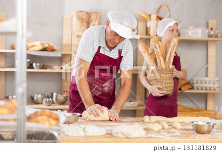 Professional aged baker kneading dough in artisan bakery Professional aged baker kneading dough in artisan bakery 131181829