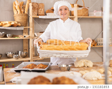 Young female baker with basket of baguettes Young female baker with basket of baguettes 131181853