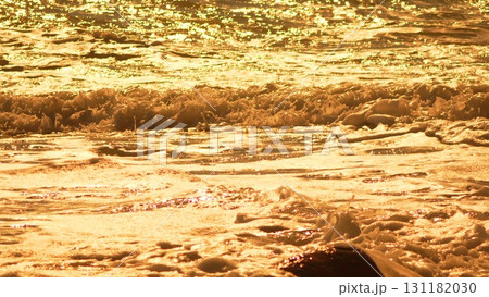 Water Gold Waves: Golden ocean water sparkles and froths on surface during scenic golden hour. 131182030