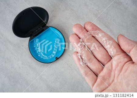 歯科矯正用のマスピースが入ったケースとアライナーを手に持っている画像 131182414