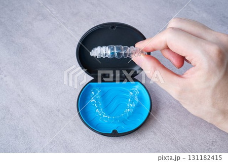 歯科矯正用のマスピースが入ったケースとアライナーを手に持っている画像 歯科矯正用のマスピースが入ったケースとアライナーを手に持っている画像 131182415