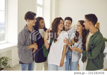Group of happy teenage boys and girls meeting after class and having fun together Group of happy teenage boys and girls meeting after class and having fun together 131182438