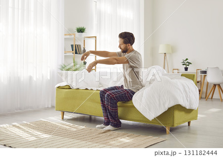 Sleepy man can't wake up, feels tired and doesn't want to get out of bed early on Monday morning. 131182444