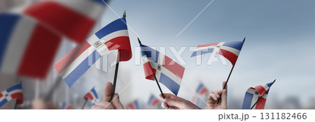 Dominicana flags in their hands on a blurred urban background Dominicana flags in their hands on a blurred urban background 131182466
