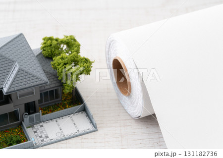 ミニチュアの家と白い壁紙シートのロールのクローズアップ 131182736
