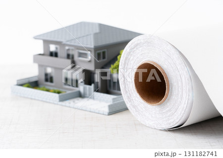 ミニチュアの家と白い壁紙シートのロールのクローズアップ 131182741