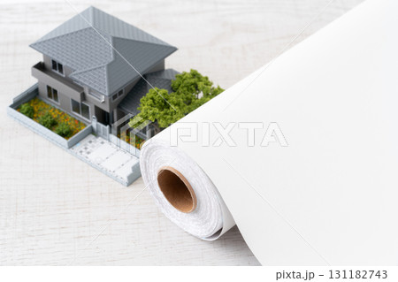 ミニチュアの家と白い壁紙シートのロールのクローズアップ 131182743