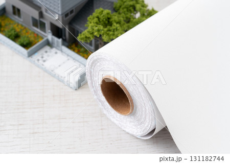 ミニチュアの家と白い壁紙シートのロールのクローズアップ 131182744