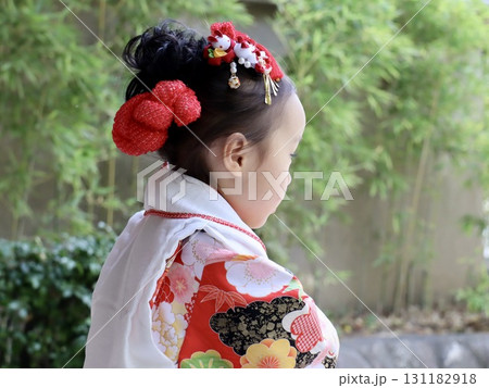初めての七五三、緊張と成長が溢れる幼い女の子の上半身後ろ姿とその横顔 131182918