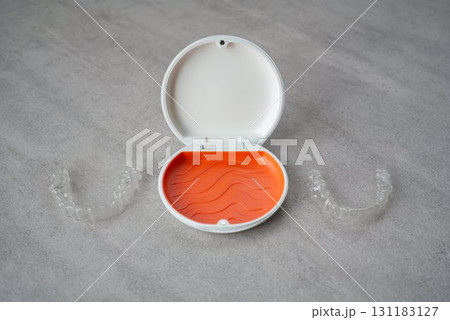 歯科矯正用のアライナーが入っているオレンジ色と白色のケース 歯科矯正用のアライナーが入っているオレンジ色と白色のケース 131183127