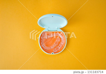 歯科矯正用のアライナーが入っているオレンジ色と白色のケース 131183714