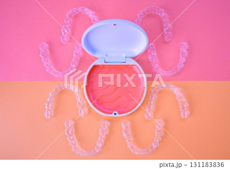 歯科矯正用のアライナーとケース、オレンジ色とピンク色の背景 131183836