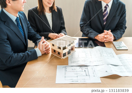 住宅模型と設計図を見ながら打ち合わせ,ミーティングをする男女のビジネスマン 住宅模型と設計図を見ながら打ち合わせ,ミーティングをする男女のビジネスマン 131183839