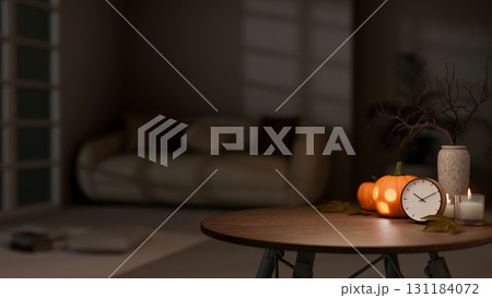 Glowing halloween pumpkin lantern with clock and lighting candle on wooden table in dark living room 131184072