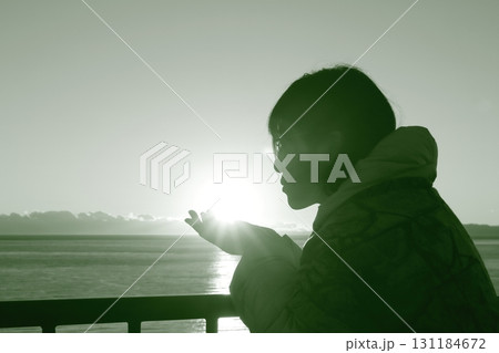 夕日を掌に載せ眺める女性のシルエット 夕日を掌に載せ眺める女性のシルエット 131184672