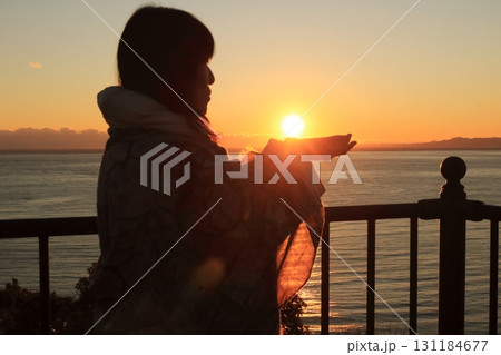 夕日を掌に載せ眺める女性のシルエット 夕日を掌に載せ眺める女性のシルエット 131184677