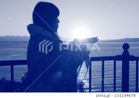 夕日を掌に載せ眺める女性のシルエット 夕日を掌に載せ眺める女性のシルエット 131184679
