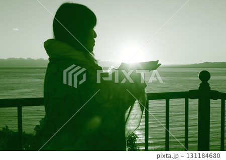 夕日を掌に載せ眺める女性のシルエット 夕日を掌に載せ眺める女性のシルエット 131184680