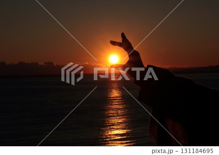 手で夕陽をつかむ人のシルエット 手で夕陽をつかむ人のシルエット 131184695
