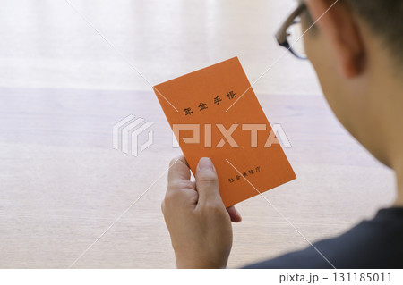 年金手帳を見つめる男性 131185011