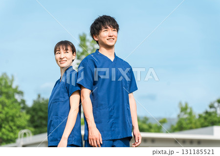 病院・施設の前にいるスクラブを着た医療従事者の男女スタッフ(作業療法士・看護師) 病院・施設の前にいるスクラブを着た医療従事者の男女スタッフ(作業療法士・看護師) 131185521