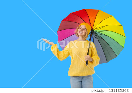 Woman in yellow sweater holds bright umbrella in clear sky 131185868