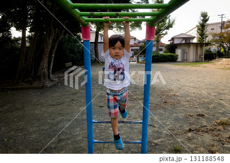 <素材>秋の公園で雲梯にぶら下がる男の子 <素材>秋の公園で雲梯にぶら下がる男の子 131188548