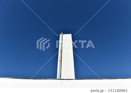 Industrial whitewashed chimney tower against blue sky Industrial whitewashed chimney tower against blue sky 131188961