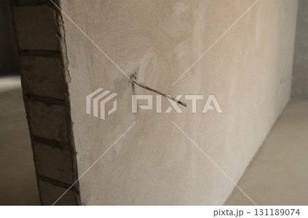 Electric wire in room sticking out of cement wall in rough repairs apartment. 131189074