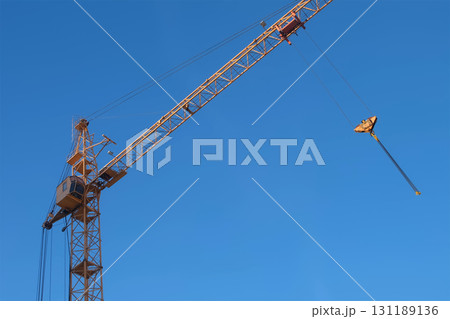 Moving yellow tower crane on construction site on blue sky background. 131189136